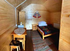 a room with a bed and a table in a cabin at Căsuțele Camping AliMar in Tîrsa