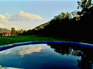 a swimming pool with a reflection of the sky in the water at Căsuțele Camping AliMar in Tîrsa