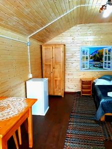 a room with a bed and a refrigerator and a table at Căsuțele Camping AliMar in Tîrsa