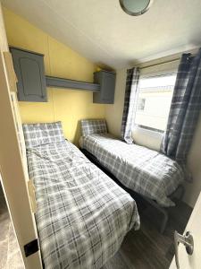 スケッグネスにあるRevamped & Upgraded 6 Berth Static Caravan on Southview Skegnessのベッド2台と窓が備わる小さな客室です。