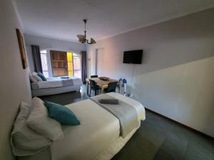 a bedroom with a large bed and a living room at 29B Zebra Street - InHimwe Guesthouse in Polokwane