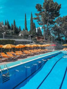 una gran piscina con sillas y sombrillas en Camping C'era Una Volta en Villanova dʼAlbenga