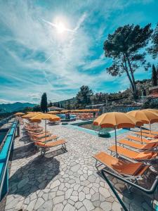 a row of lounge chairs and umbrellas next to a swimming pool at Camping C'era Una Volta in Villanova dʼAlbenga