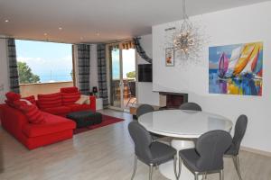 a living room with a red couch and a table and chairs at Favola Bella The panoramic penthouse in Bardolino