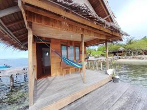 a hammock hanging from a house on a dock at Guest Hause Lalosi Arborek Raja Ampat in Besir