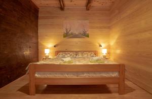 uma cama num quarto de madeira com 2 candeeiros em Kuća za odmor Slunjčica em Slunj