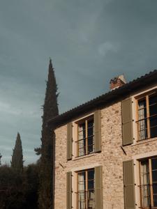 a building with green shuttered windows and a tree at Borgo SAN SONNEA Lake Garda in Torri del Benaco