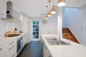 une cuisine blanche avec un évier et une cuisinière dans l'établissement Paddington Cottage - A Classic Queenslander Stay, à Brisbane