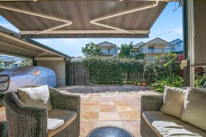 une terrasse avec des chaises en osier et un parasol dans l'établissement Paddington Cottage - A Classic Queenslander Stay, à Brisbane