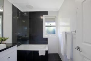 une salle de bain blanche avec une baignoire et une fenêtre dans l'établissement Paddington Cottage - A Classic Queenslander Stay, à Brisbane 15 autres photos