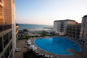 a large swimming pool next to a beach with buildings at Частно студио в комплекс Поморие Ризорт in Pomorie