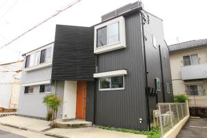 a black house with a orange door on a street at trive osu east 駅チカ 大須観音通商店街スグ in Nagoya