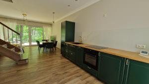 a kitchen with green cabinets and a dining room with a table at Giruliai Amber Dune in Klaipėda +3 photos