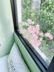 - une fenêtre avec des fleurs roses et un oreiller dans la chambre dans l'établissement Tree House, à Tainan