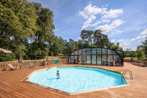 a person standing in a swimming pool next to a glass house at Huttopia De Meinweg in Herkenbosch