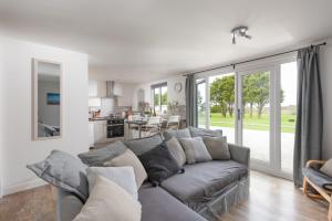 a living room with a gray couch and a kitchen at Wheal Jewel - Hot Tub - On-site Activities - Free WiFi - Parking in Helston +18 photos