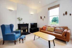 a living room with a leather couch and a chair at Veeve - Charming Hampstead Apartment in London