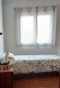 a bedroom with a bed and a window with curtains at Casa roja in Camariñas