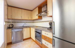 eine Küche mit Holzschränken und einem Edelstahlkühlschrank in der Unterkunft 3 Bedroom Nice Home In Santa Pola in Santa Pola