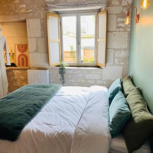 een bed in een kamer met een bank en een raam bij Gîte verveine bain nordique jacuzzi l écrin de verdure chinon in Ligré