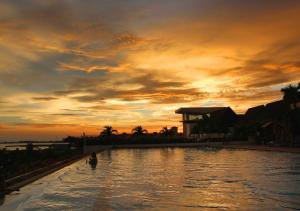 a pool with a person in the water at sunset at Holiday Inn Melaka, an IHG Hotel in Melaka