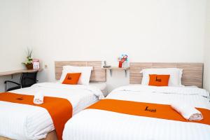 two beds in a room with orange and white at L'cost Homestay in Sawah