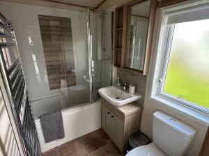 La salle de bains est pourvue d'un lavabo, de toilettes et d'une douche. dans l'établissement Luxury Lake District Holiday Home-Sleeps 4, à Cockermouth
