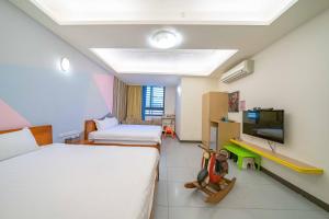 a hotel room with two beds and a tv at Chikan Fun Guesthouse in Tainan