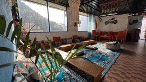 sala de estar con sofá, mesa y sillas en Peace Inn Hostel & Kasolview Homestay en Kasol