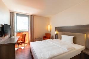 um quarto de hotel com uma cama, uma secretária e uma janela em IntercityHotel Berlin Airport Area North em Schönefeld