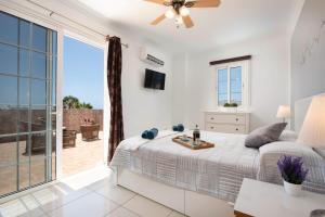 a white bedroom with a bed and a large window at Villa Naranja with private heated pool, sea views, air conditioning, terrace, ITV and BBC channels, Wifi in Callao Salvaje