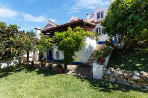 a white house with a tree in the yard at WHome Ericeira Private Villa in Mafra