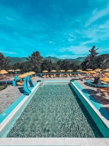 uma piscina com escorrega aquático, cadeiras e guarda-sóis em Camping C'era Una Volta em Villanova dʼAlbenga