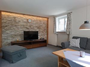 a living room with a tv and a brick wall at Ferienwohnungen Spiß in Fischen