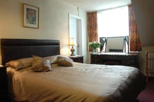 a bedroom with a large bed with a dresser and a window at The Bebington in Bebington