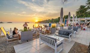a group of people sitting on the beach watching the sunset at Eurocamp Mobile Homes at Campsite Valkanela in Funtana