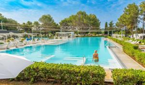 a woman is standing in a swimming pool at Eurocamp Mobile Homes at Campsite Valkanela in Funtana