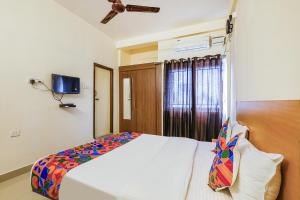 Un dormitorio con una cama y un televisor en la pared. en Fabhotel Tristar Residency - Nr Tambaram Railway Station, en Chennai 24 fotos más