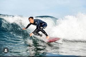a man riding a wave on a surfboard in the ocean at Charming Cornish Cottage, Portreath, Dogs Welcome in Redruth