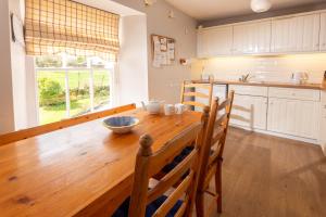 a kitchen with a wooden table with chairs and a window at Myrtle Cottage in Chapel Stile