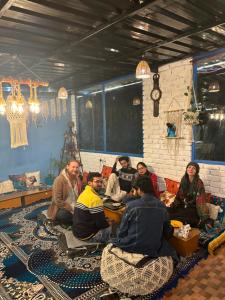 un grupo de personas sentadas alrededor de una mesa en una habitación en Peace Inn Hostel & Kasolview Homestay en Kasol