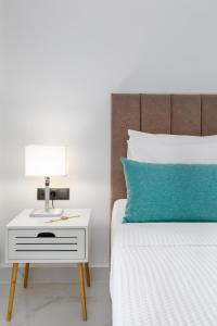 a bed with a white nightstand and a blue pillow at Greek Rooms 1 in Kallithea Halkidikis +6 photos
