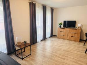 ein Wohnzimmer mit einem TV und Holzböden in der Unterkunft KOSY Appart'Hôtel 7ème Art in Saint-Avold