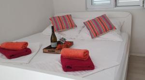 ein weißes Bett mit einer Flasche Wein und zwei Kissen in der Unterkunft Apartmani Sara Marija in Karlobag