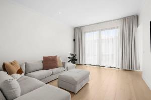 a white living room with a couch and a stool at Casa del Candelabra - Light-Filled Luxury Retreat Minutes from Town in Bellbrae