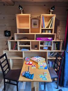 un tavolo in legno con due sedie e una libreria di Le Chal'étincelle a Valdeblore
