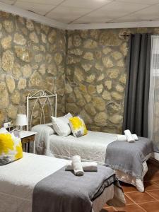 a bedroom with two beds and a stone wall at Hostal Paquito in Vejer de la Frontera
