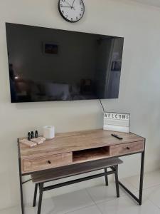 a desk with a tv on a wall with a clock at Lake View Wind SMDC Tagaytay in Tagaytay +16 photos