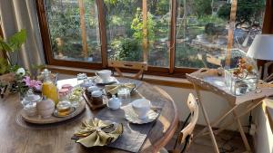 a dining room table with a tea set in front of a window at L'Orme Seul, Maison d'hôtes in Vineuil