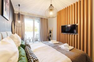 Schlafzimmer mit einem Bett und einem TV an der Wand in der Unterkunft Loft House by Perłowa Przystań Rent in Kołobrzeg